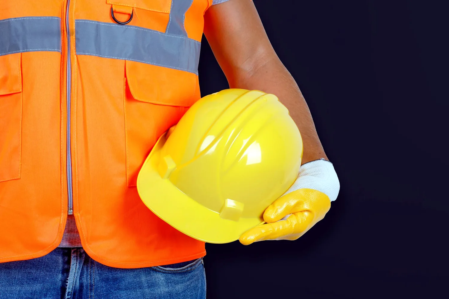 Trabalhador com colete refletivo segurando capacete de segurança